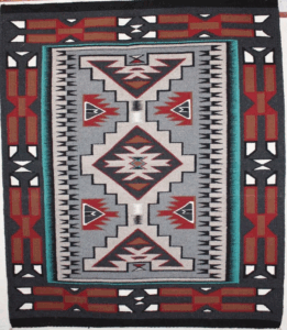 A colorful geometric patterned rug with red, white, and black designs.