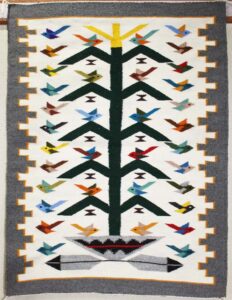 Colorful woven rug featuring a tree with birds design.