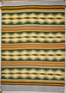 A textile with green, orange, and cream geometric patterns.
