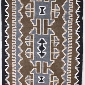 Traditional geometric patterned rug with earthy tones of brown, black, and white.