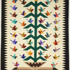 A colorful quilt with a tree and bird motif on a white background.