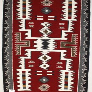 Traditional rug with geometric patterns in red, white, and black.
