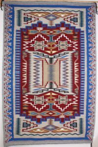 Intricately patterned red, blue, and beige woven rug with geometric designs.