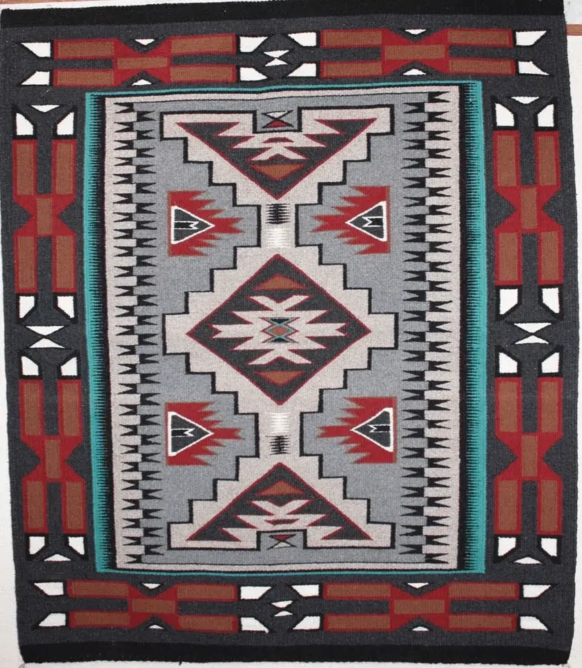 A colorful geometric patterned rug with red, white, and black designs.